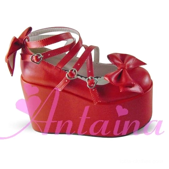 Red patent leather Lolita platform shoes front close-up three-quarter view highlighting heart-shaped red stone buckles, heel strap bow decoration, and thick waterproof platform sole