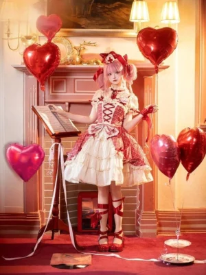 Full-body front view of red plaid cake lolita JSK dress with tiered ruffled skirt, model wearing pink twin-tails in vintage room setting with fireplace and heart balloons