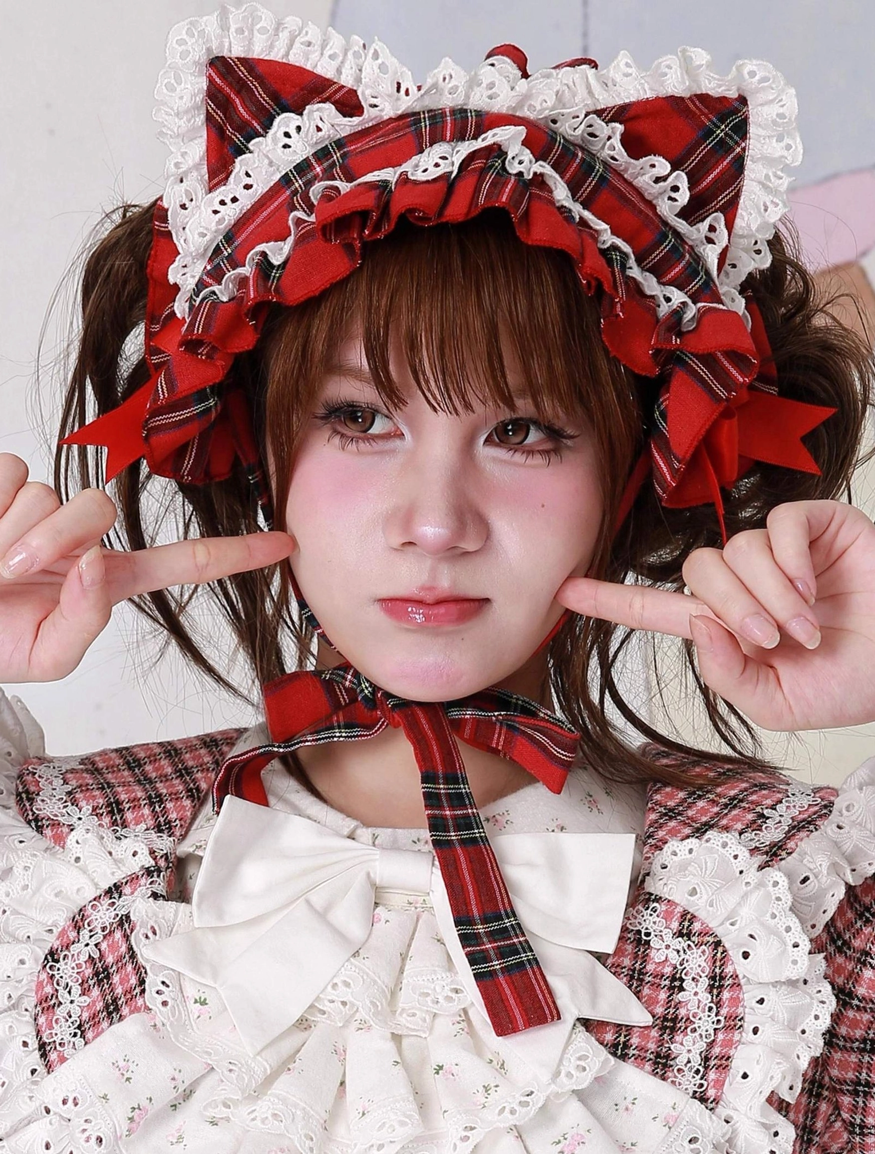Red plaid cat ear sweet lolita hairband on model wearing coordinated red plaid lolita blouse, frontal close-up with finger gun gestures, showcasing matching tartan pattern between headdress and outfit for cohesive sweet lolita coordinate