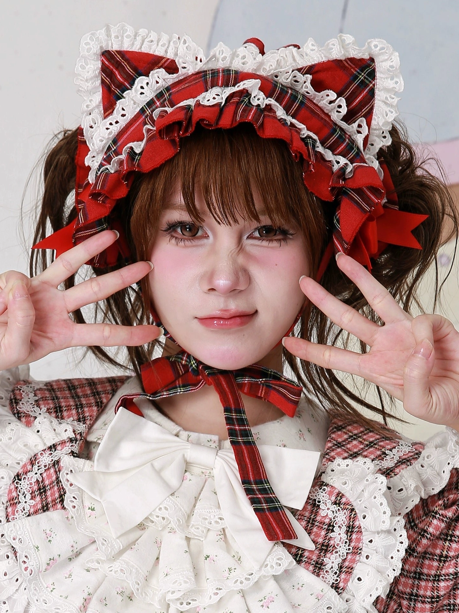 Red plaid cat ear lolita headdress top view with peace sign gesture, model wearing red plaid lolita blouse with large white bow, clear view of layered lace details and plaid cat ear construction, frontal close-up