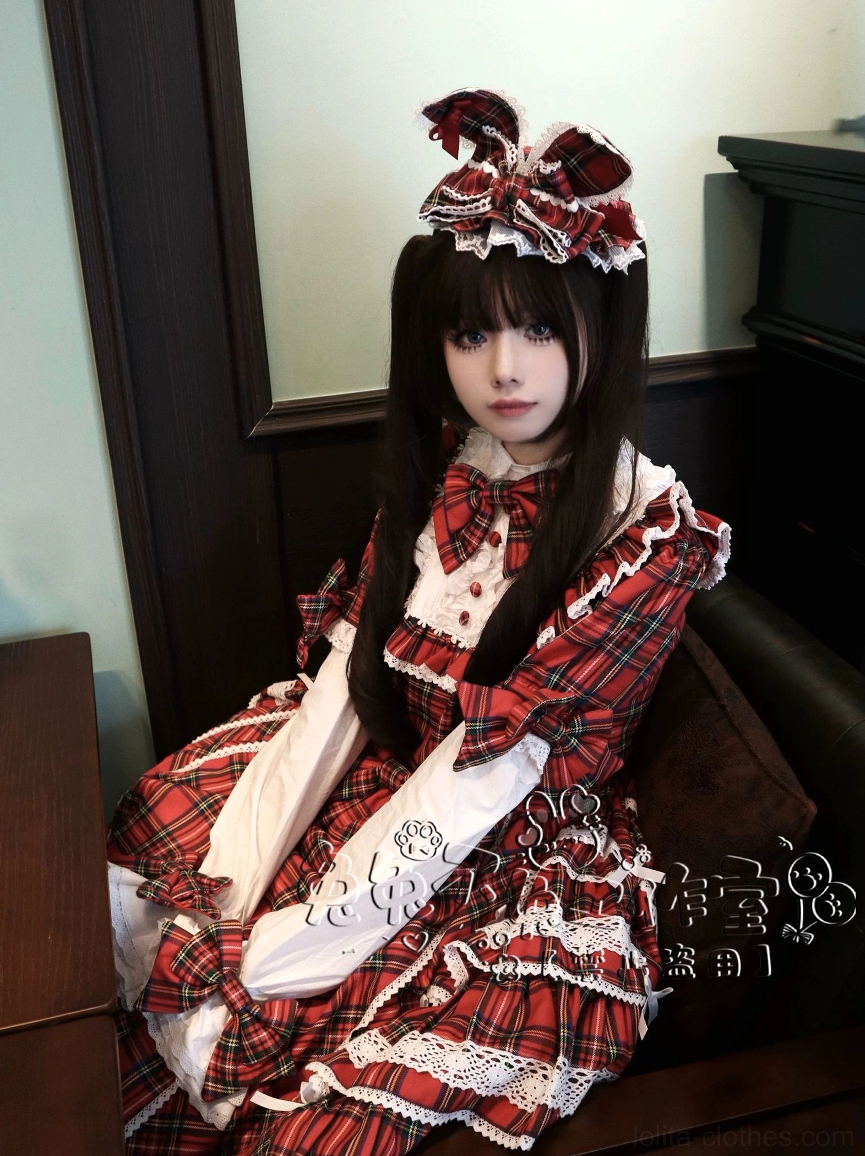 Front view of female model wearing red plaid Lolita bunny ear hair clip accessory in vintage interior setting with dark furniture paired with red plaid Lolita dress outfit
