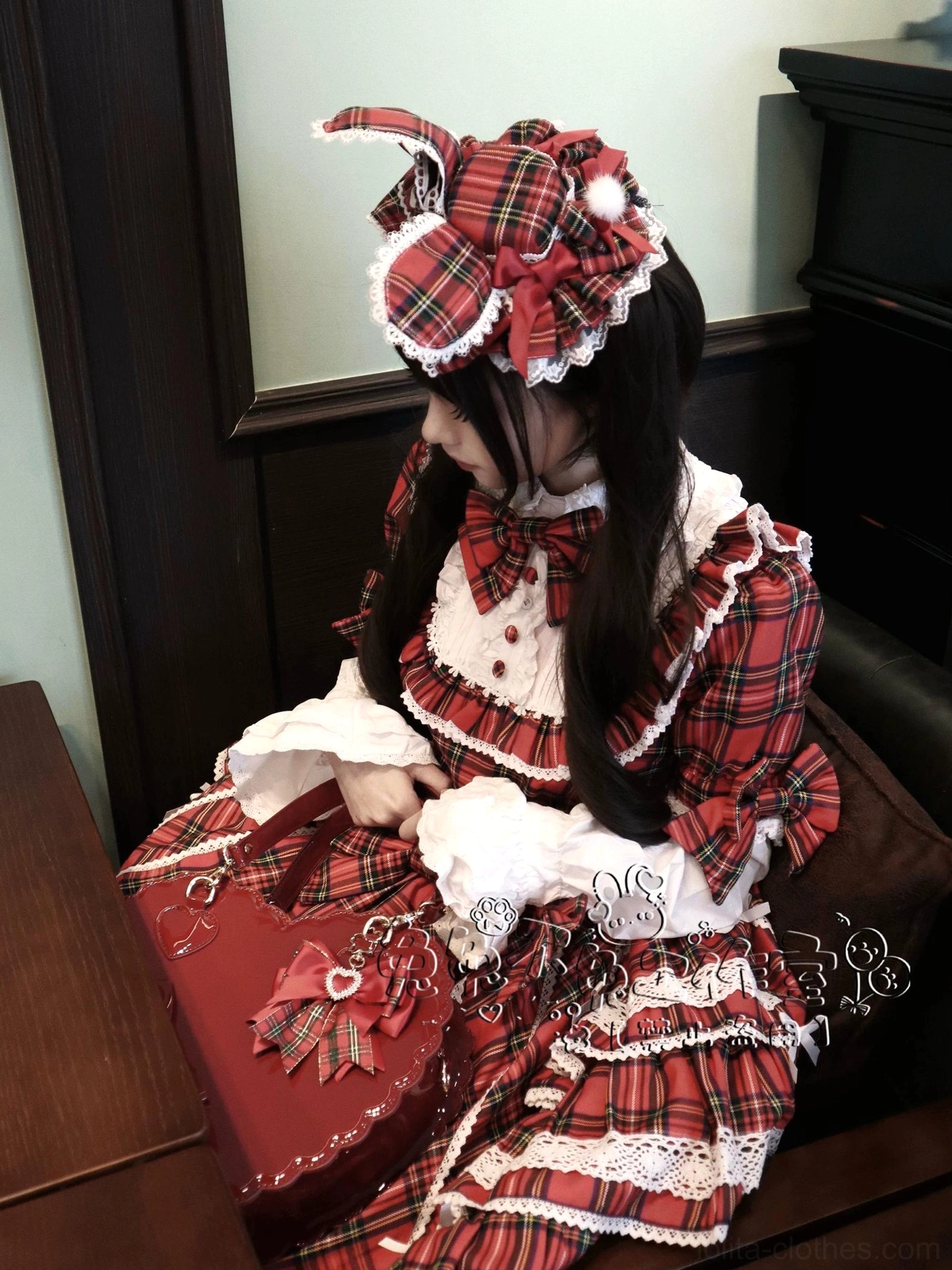 Female model wearing red plaid Lolita bunny ear hair piece side profile view in vintage indoor room with dark wooden furniture coordinated with matching red tartan plaid dress