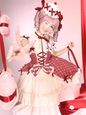 Close-up front view of pink curly twin-tailed model wearing red plaid lolita cake jumper skirt with cross cake hair crown, peace sign pose with pink gift box background