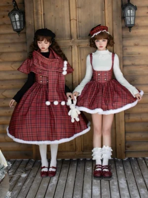 Red plaid Lolita twins JSK set with long and short versions, white pom-pom trim, detachable cape with scarf, boned waist support, front view in snowy wooden cabin setting