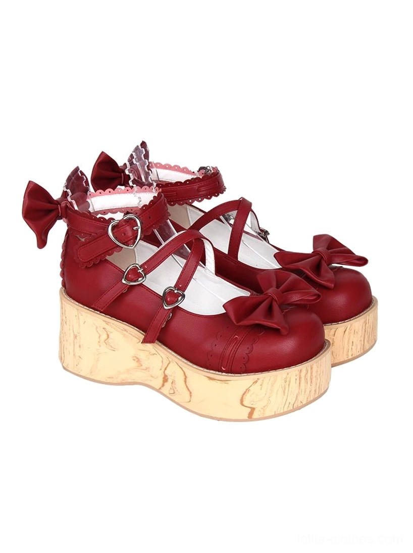 Red Princess Lolita platform shoes featuring heart-shaped metal buckles, decorative toe bow, double-cross straps with lace trim, and wood grain platform sole, displayed from three-quarter angle