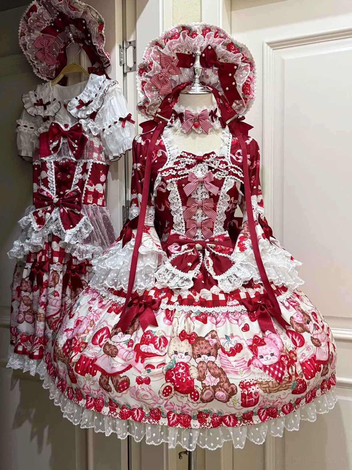 Red-themed strawberry bear print sweet lolita OP dress front display on mannequin with deep red bows and lace trim, square neckline with heart-shaped lace detail, gathered full skirt