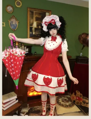 Three-quarter front view of red strawberry Lolita JSK dress with contrast lace collar, detachable red bow, strawberry printed hem, and matching cute printed socks