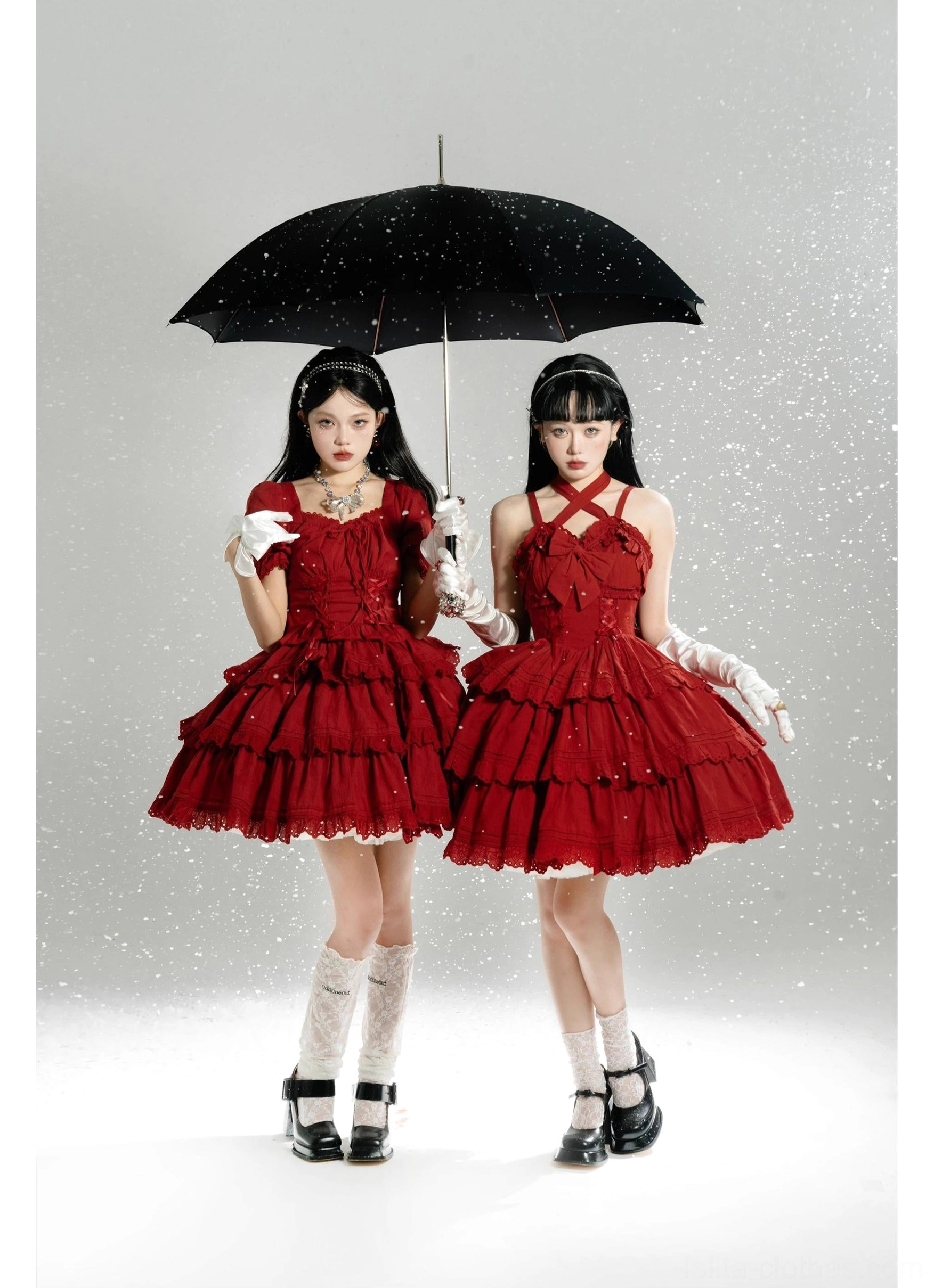 Matching red sweet lolita dress set with cross halter neckline, lace-trimmed tiered skirts, large back bows, worn by identical twin models with leather Mary Jane shoes in snowfall effect