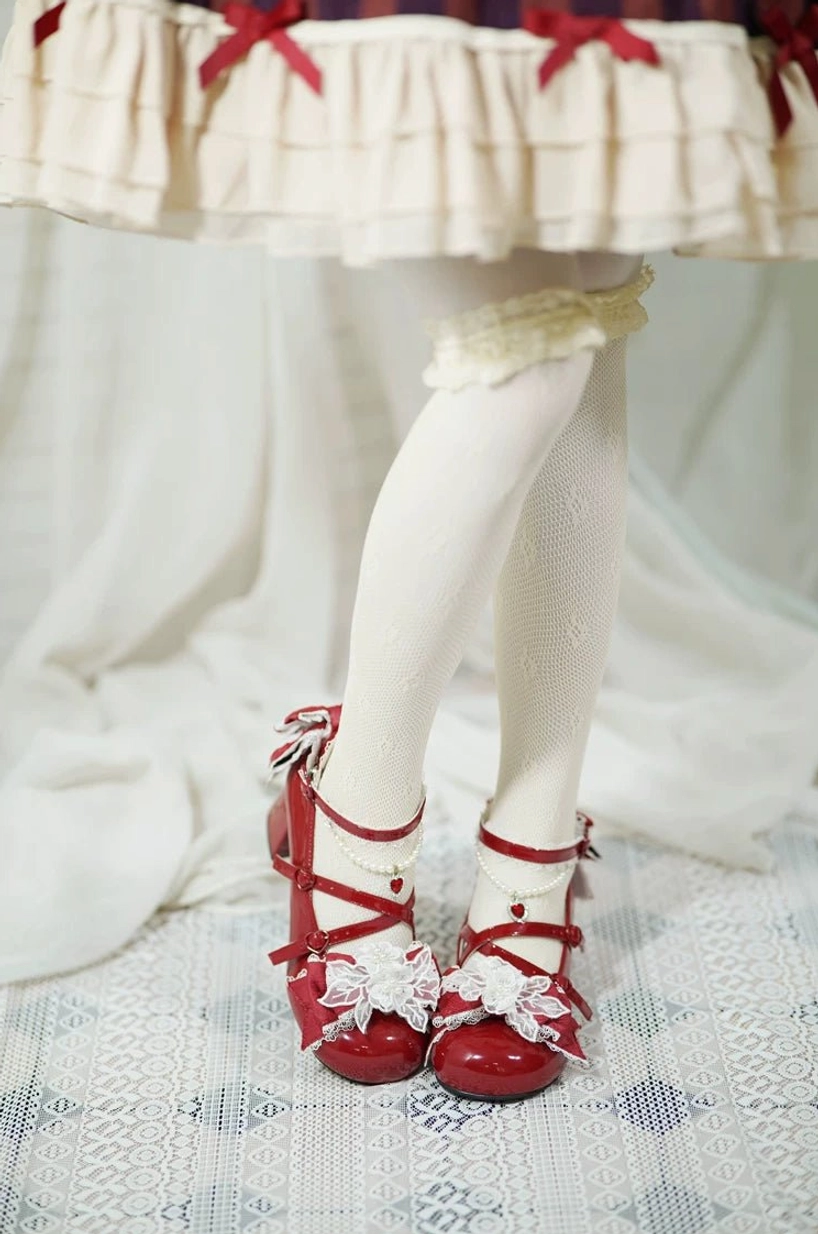 Red patent leather sweet Lolita wedding heels on model's lower legs showing tiered ruffled skirt lace garter and stockings, bright red floral toe accents and cross ankle straps