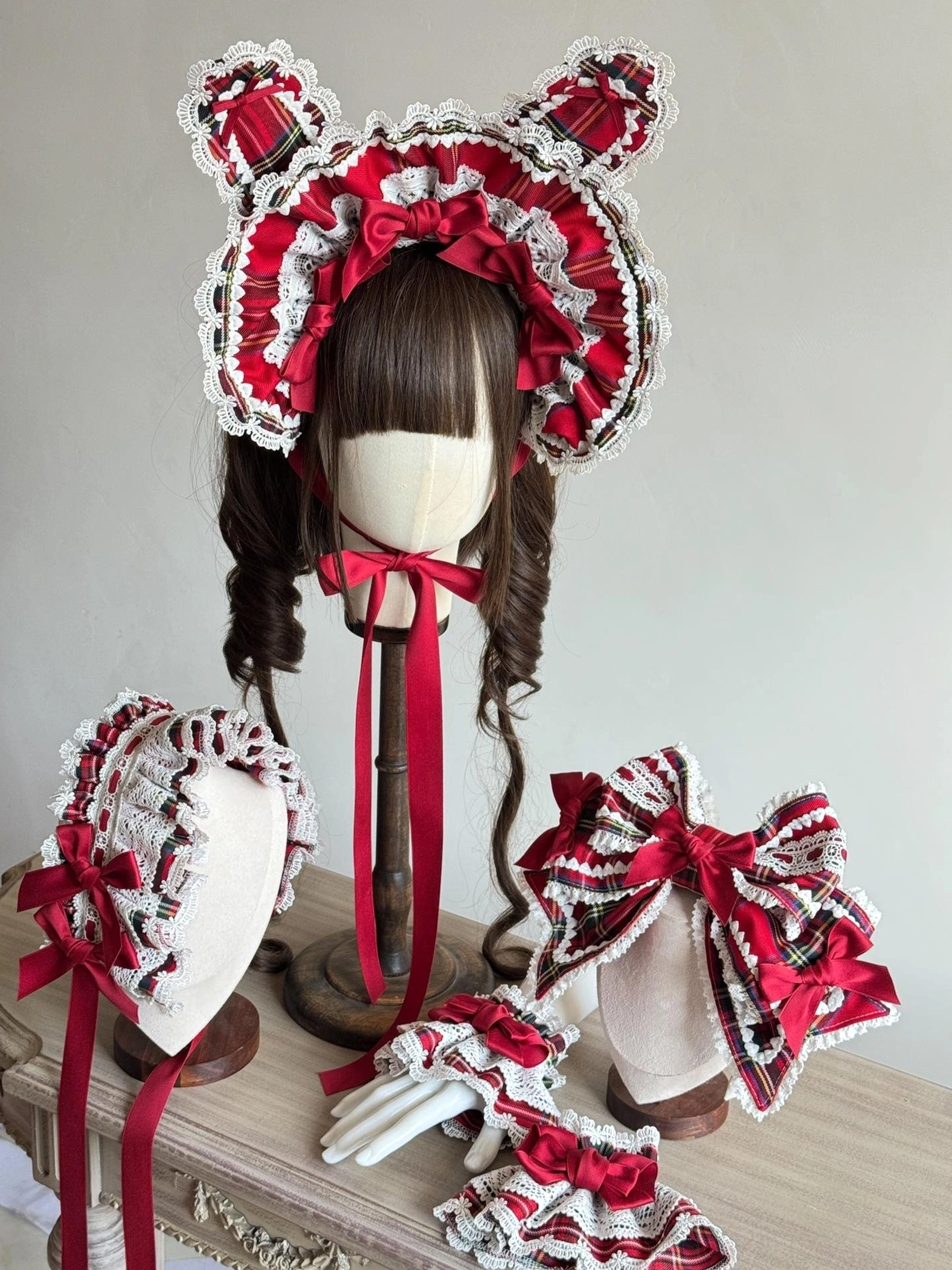 Complete red tartan Lolita headdress accessory set featuring wire-edged bunny ear BNT bonnet, layered hair bow with satin details, ruffled headband, and coordinated elastic cuffs displayed on light wooden surface with neutral background
