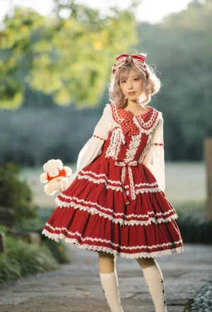 Vintage red lolita jumper skirt dress styling outdoors with blonde model wearing white blouse knee-high socks and matching hair bow