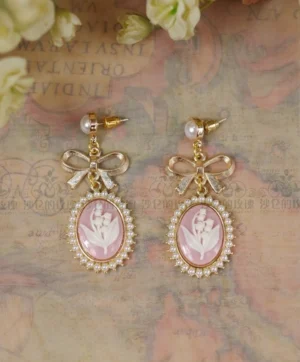 Retro cameo Lolita drop earrings with gold bow and lily of the valley pendant flat lay on vintage map background