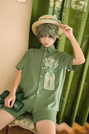 Vintage botanical embroidery lolita blouse in sage green with white jarred floral motif on chest, model wearing straw hat, close-up sitting shot with detachable green bow accessory