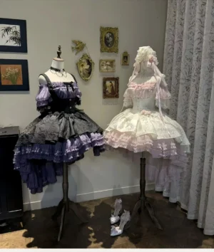 Gothic Lolita boned JSK dresses displayed on mannequins showing multi-layered high-low ruffled skirts with off-shoulder bodice in vintage exhibition gallery space