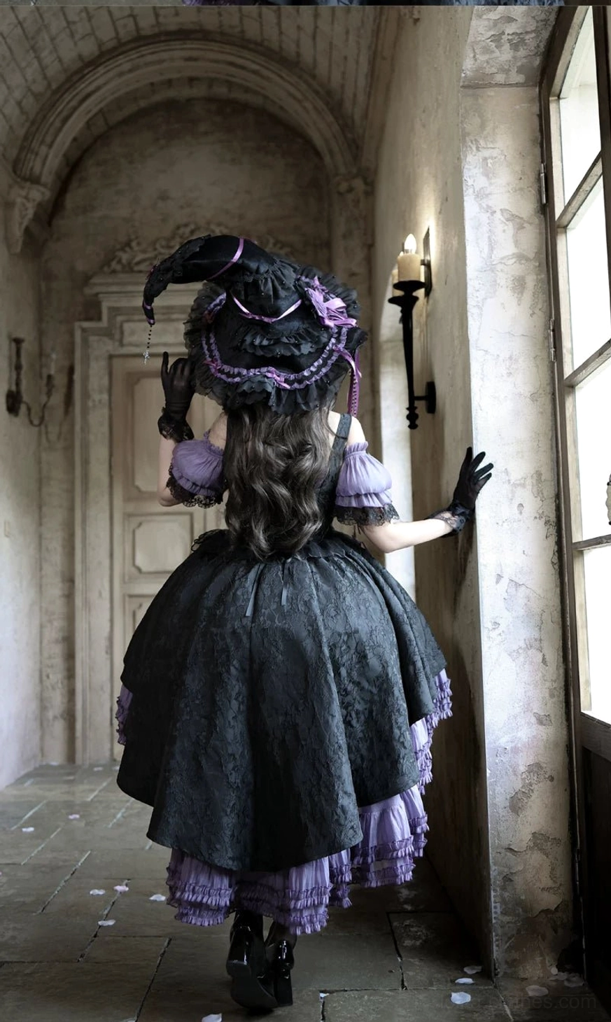 Back view of black-purple Gothic Lolita boned JSK dress showing high-low ruffled skirt with purple trim, witch hat and long gloves in European hallway