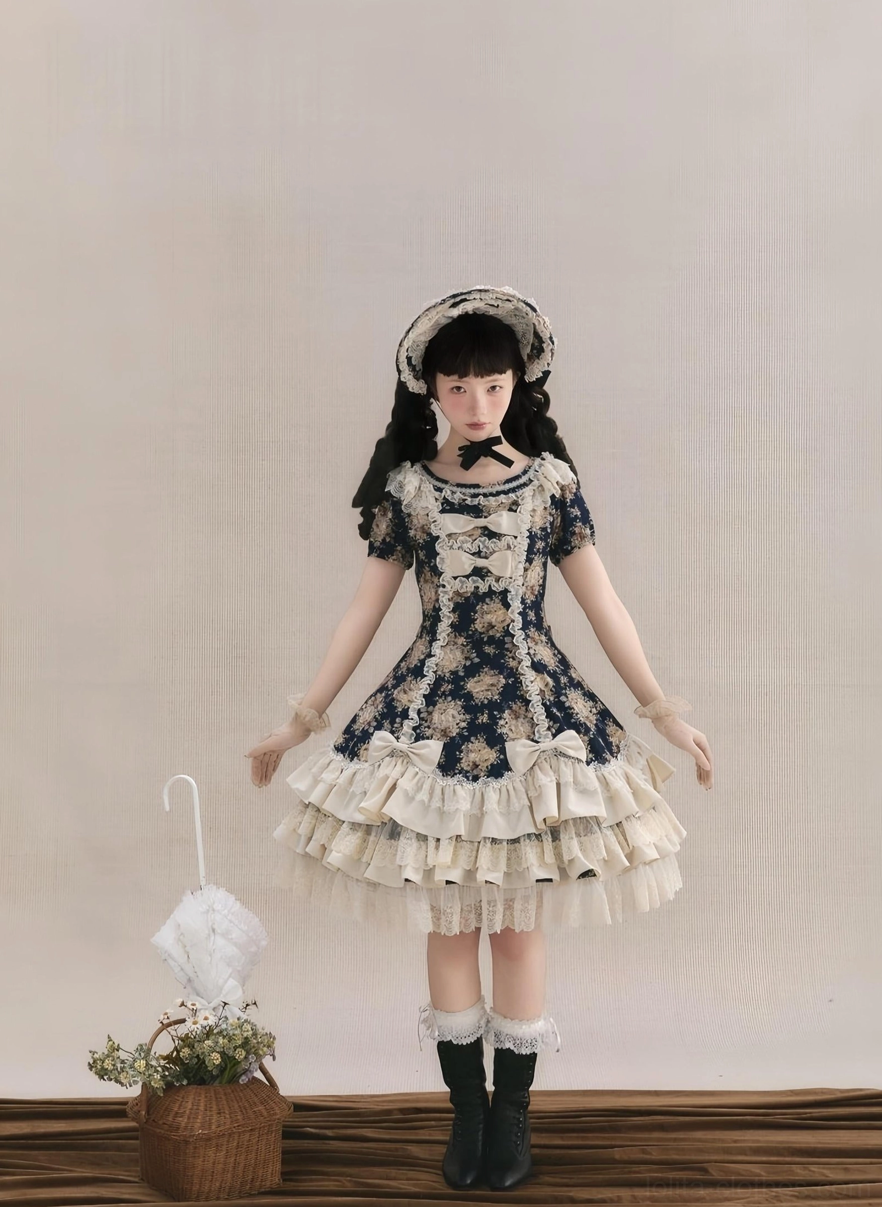 Old School Lolita OP dress with layered cream ruffled skirt, dark floral fabric, and matching bonnet in studio setting