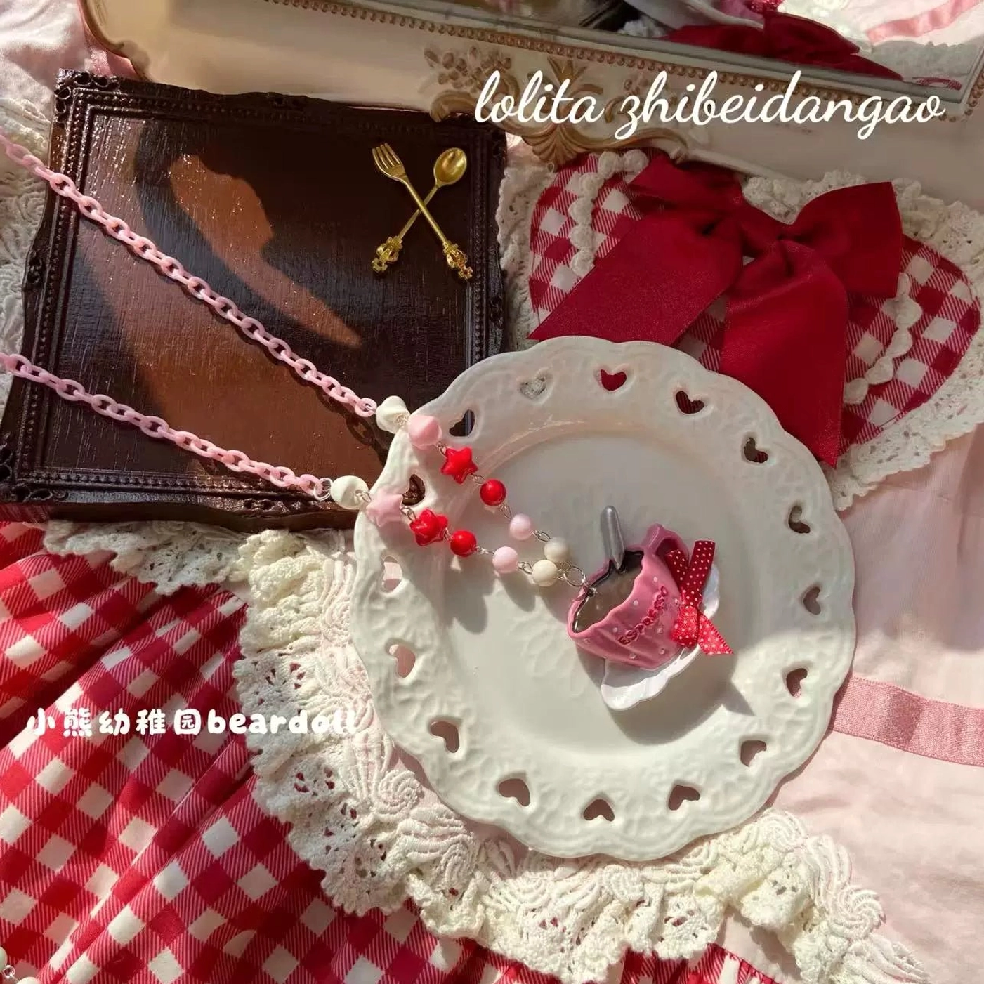 Rose red Lolita necklace featuring mini pink coffee cup pendant with red bow and beaded metal chain displayed on white decorative plate with vintage lace