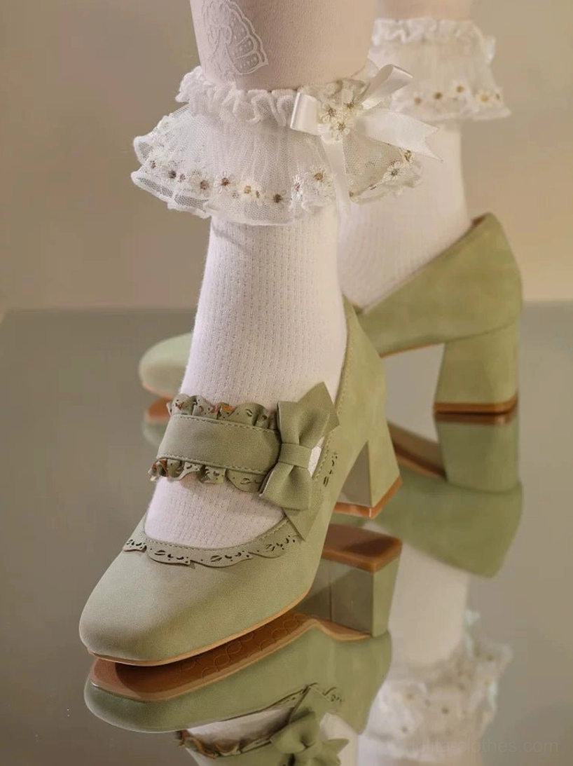 Sage green lolita chunky heel mary jane shoes with bow and ruffled trim on ankle strap and square block toe in suede finish, low close-up side view of worn shoes with ruffled frill socks and pearl embellishments