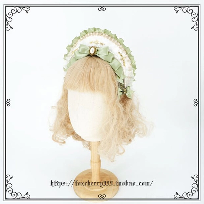 Sage green Lolita headband with mini top hat element scalloped lace edge central pearl ornament and matching satin bows on blonde wig mannequin