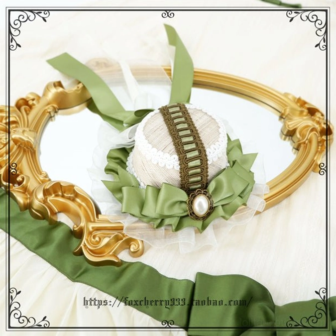 Sage green Lolita mini top hat headdress with scalloped lace trim pearl drop ornament and ruffled collar details displayed on vintage golden mirror