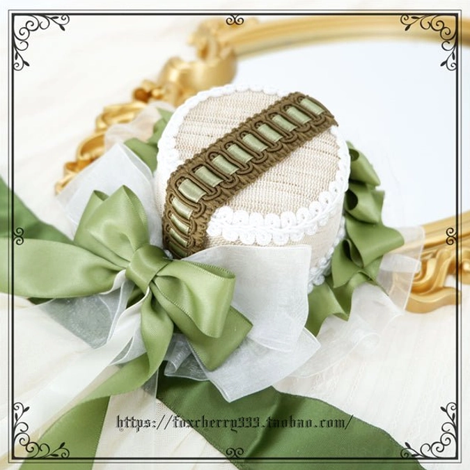 Sage green Lolita mini top hat headdress front overhead close-up showing woven decorative strap large satin bows and layered organza details