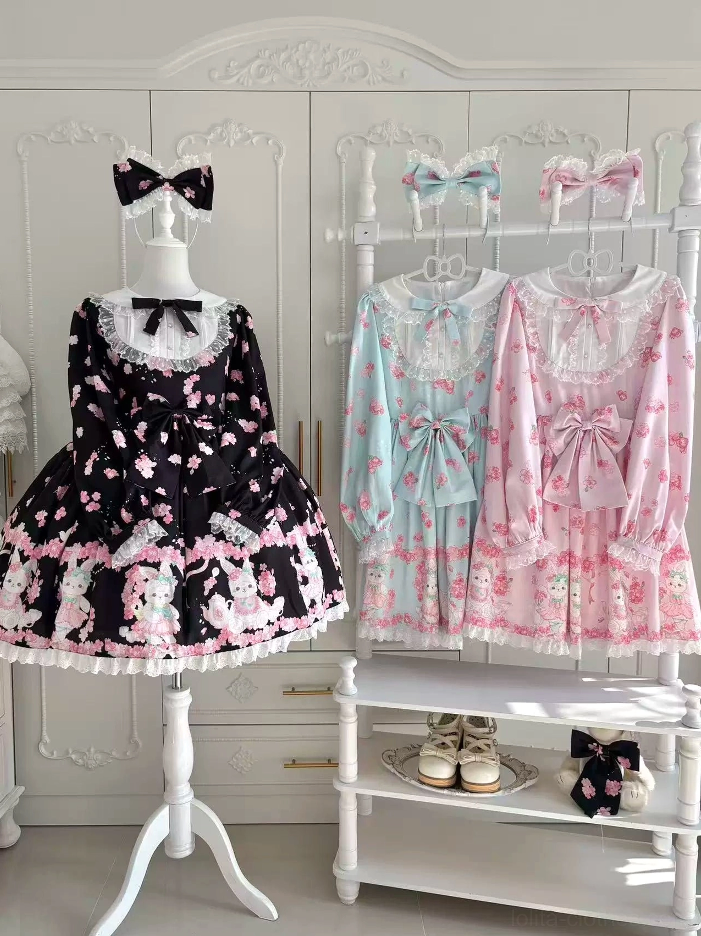 Multiple Sakura Bunny Lolita OP dress options in different color variations displayed in vintage white wardrobe closet setting showing cherry blossom and rabbit print details with lace trim