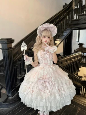 Pink sweet Lolita JSK dress with white lace trim and large front satin bow worn on vintage wooden staircase