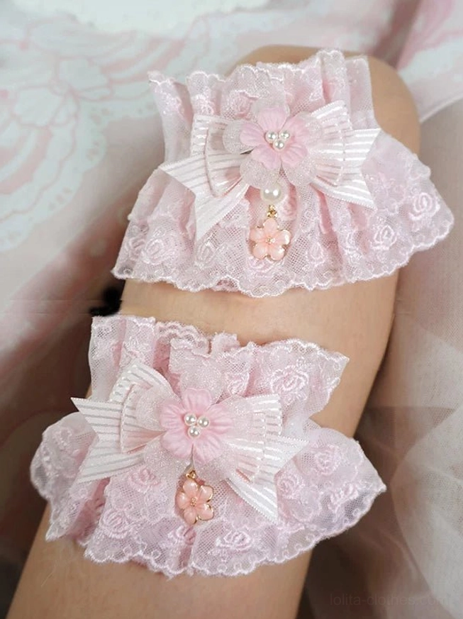 sakura pink sweet lolita lace wrist cuffs close-up worn on hand with rose embroidery, striped satin bow, and pearl flower pendant tassel detail