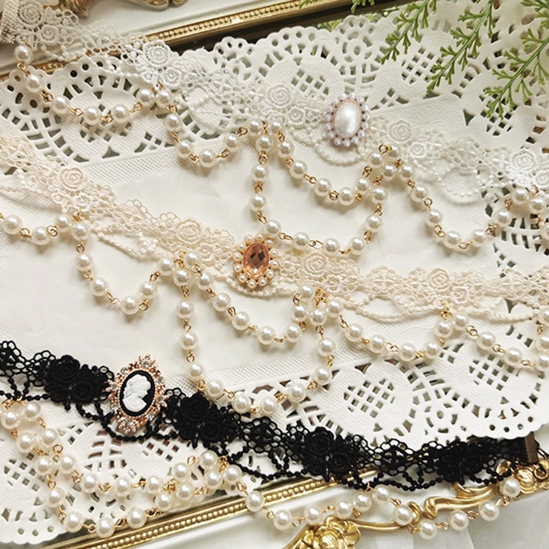 Two styles of Sally's Garden lolita pearl lace necklaces including ivory pearl lace with gem brooch and black lace cameo pearl choker with gold trim on vintage frame