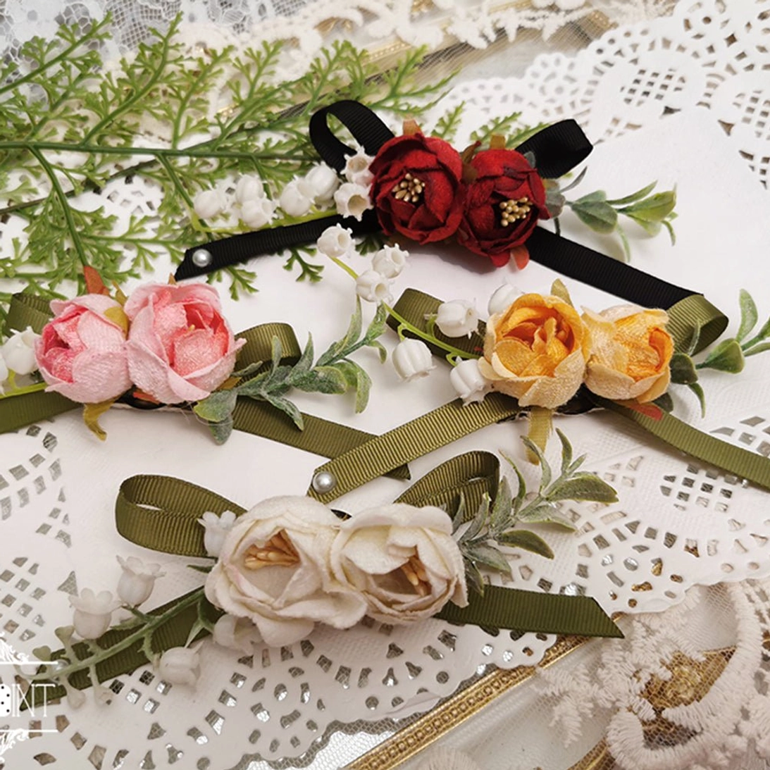 Sally's Garden lolita flower bow brooches and accessories flat lay collection displayed on vintage lace table mat with artificial roses pearl chains and satin ribbon bows