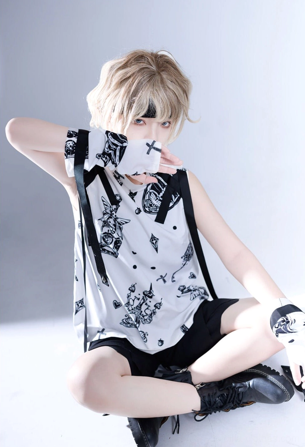 Shadow Story Ouji lolita sleeveless gothic shirt with black and white strawberry wing print, detachable cuffs and ribbon accessories, modeled by blonde male in sitting pose with grey studio backdrop