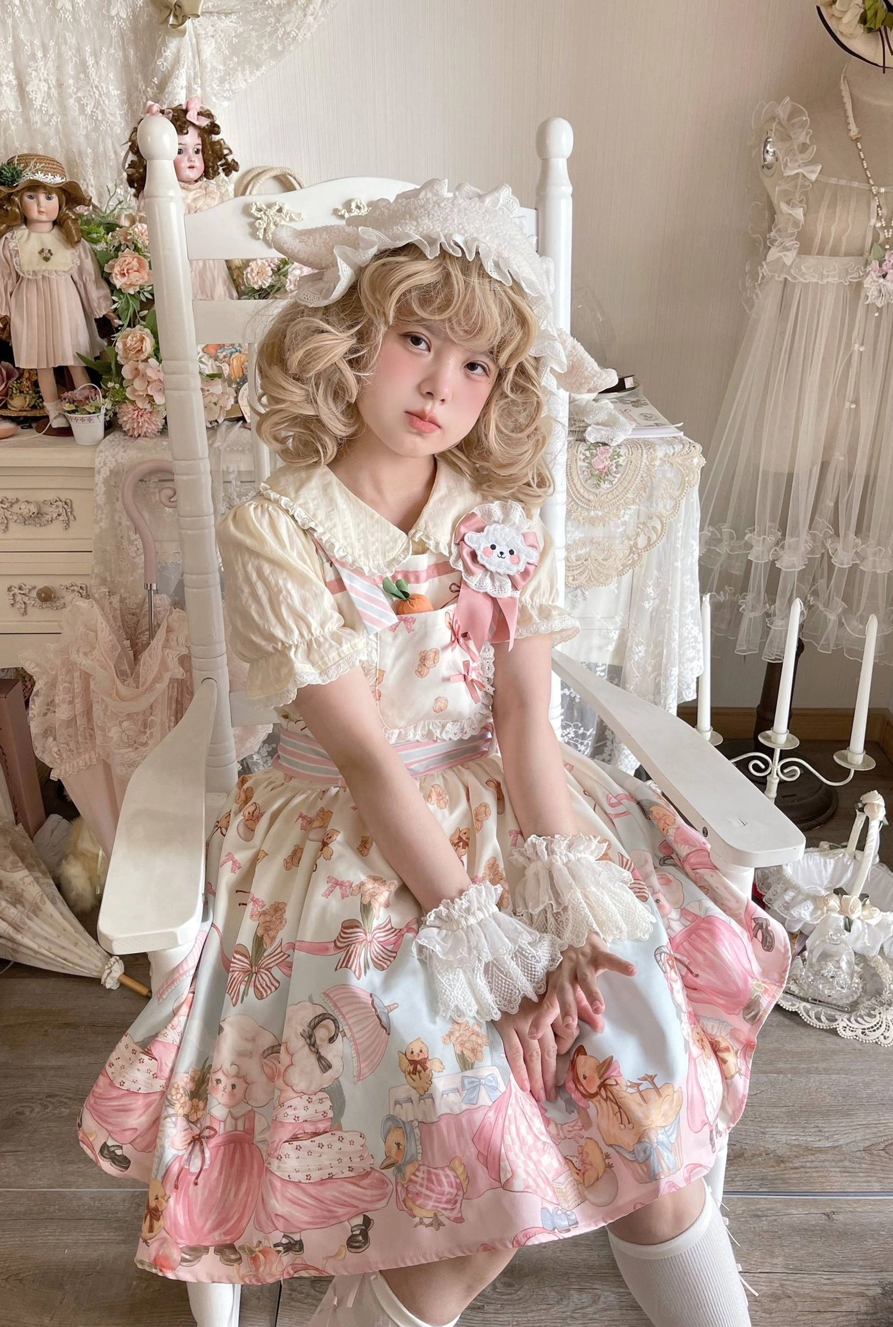 Pink-toned Sheep Pattern Lolita JSK three-quarter sitting view curly blonde model lace bonnet white lace gloves antique dollhouse-style bedroom vintage furniture ruffled sleeves