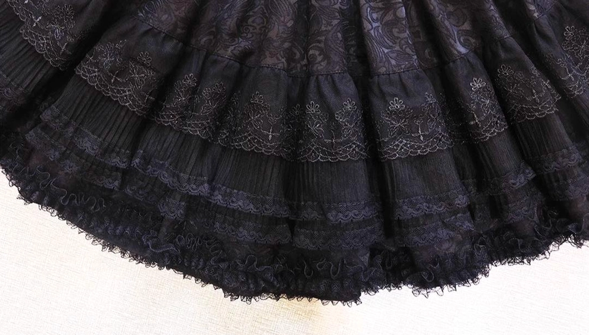 Short gothic lolita blouse and corset set close-up showing bishop sleeve detail, white bow necktie, white skeleton-style corset decoration, ruffled short dress hem, and lace elements