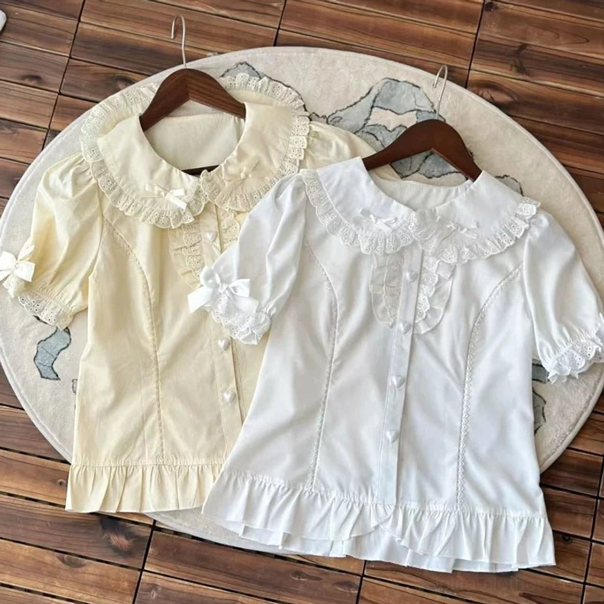 Two short sleeve lolita blouses beige white peter pan collar lace ruffled hem tiny bow details on sleeves flat lay wooden hanger display