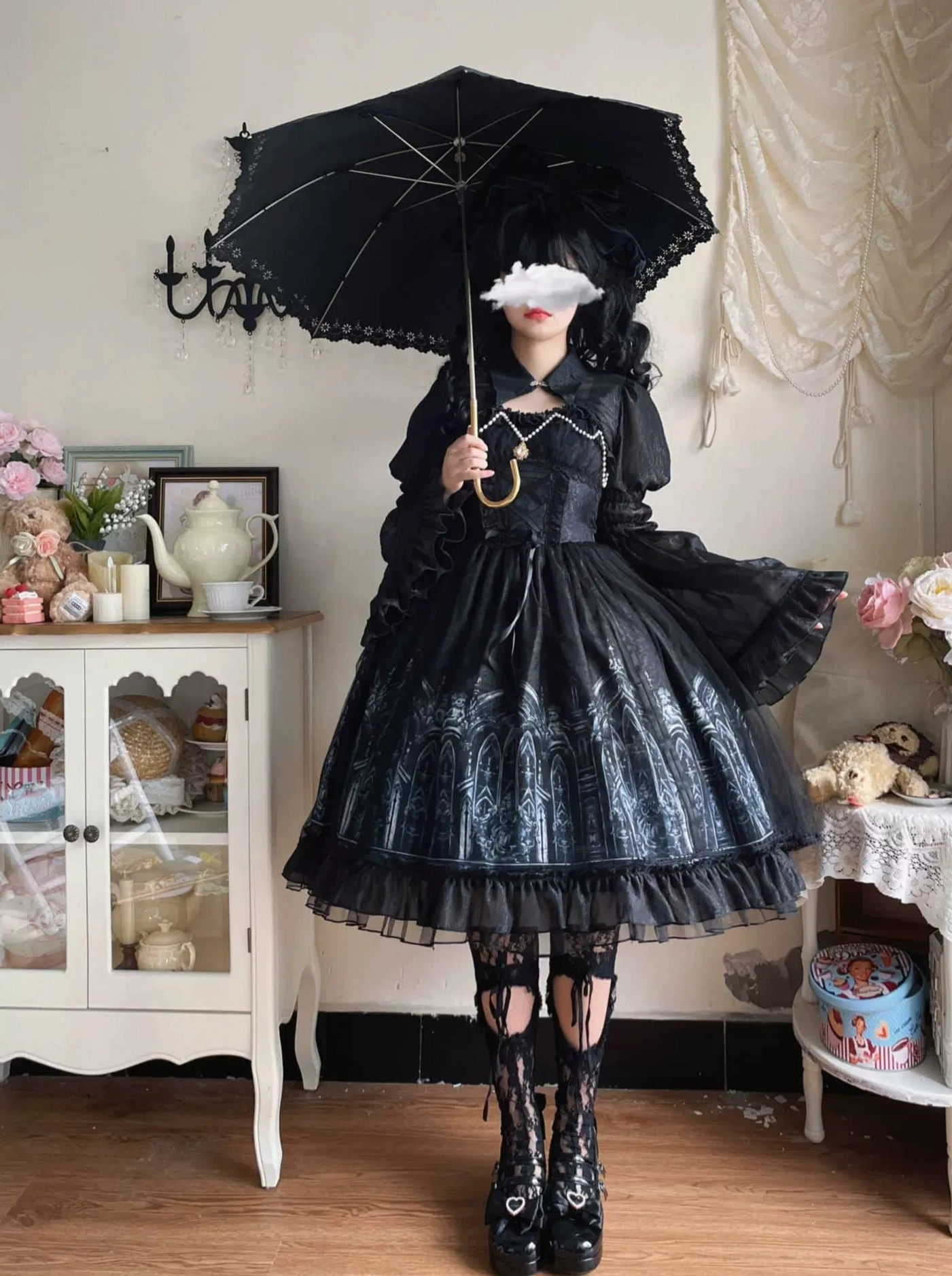Model holding open black gothic parasol wearing Silent Night lolita ensemble, displaying sheer flared ruffled sleeves, layered ruffled skirt hem, and complete gothic coordination