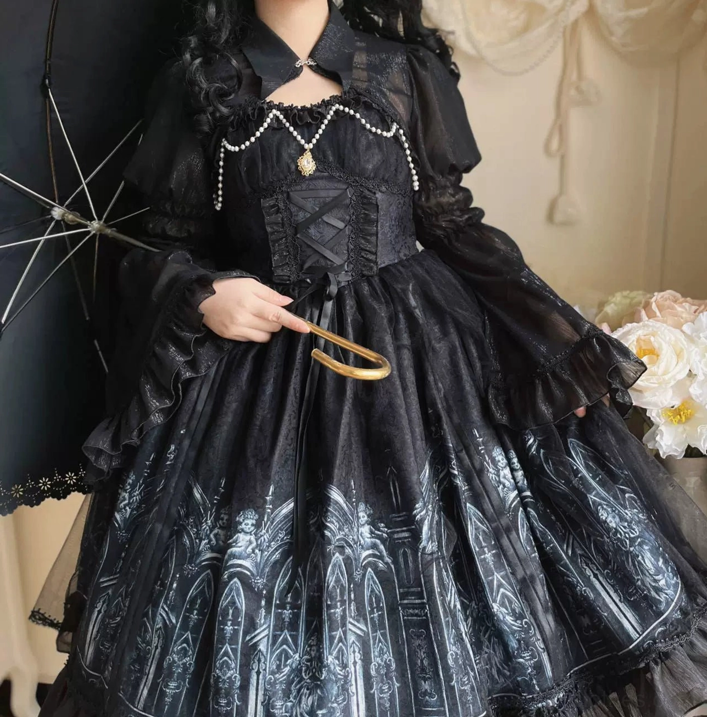 Close-up half-body shot of Silent Night gothic lolita dress showing pearl chest trim with gold pendant, silver church print cathedral architecture detail on black skirt fabric, gold parasol handle