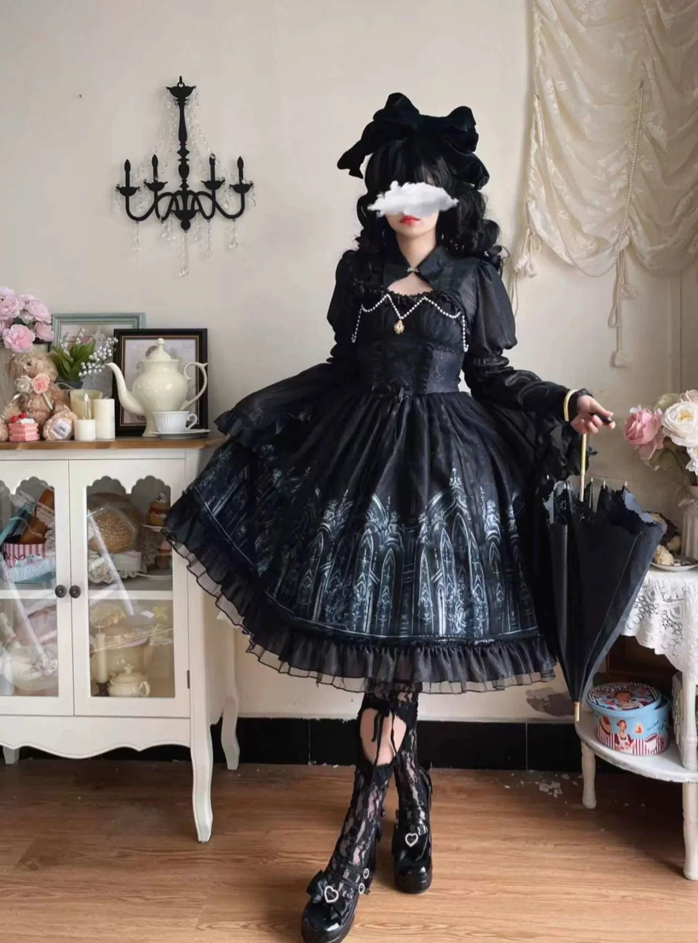Model posing in Silent Night gothic lolita dress with three-quarter side angle view, holding black parasol, showing church print detail and layered ruffled hem with matching black hair bow
