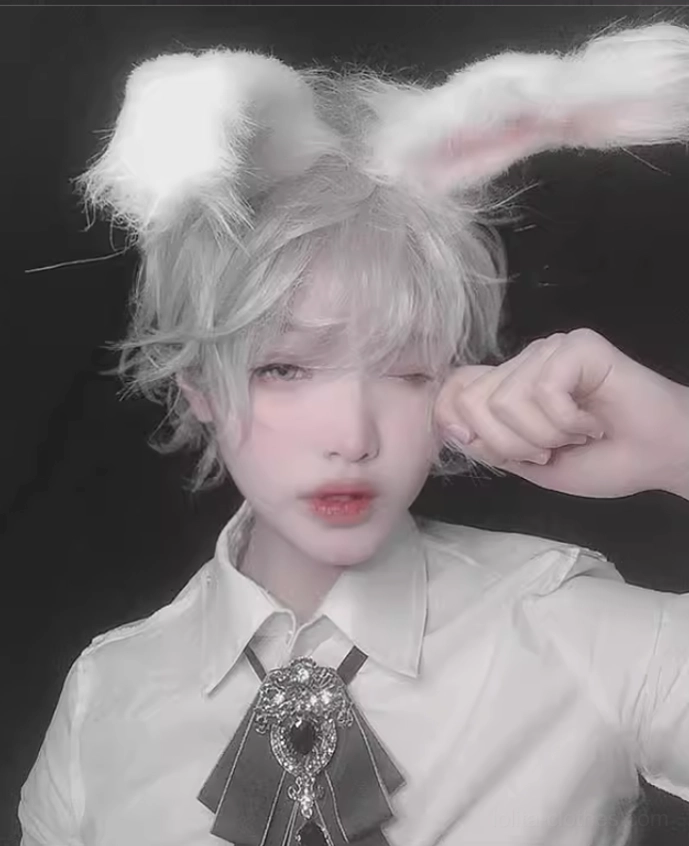 Three-quarter angle of silvery gray short curly wig with fluffy rabbit ears on model with playful expression