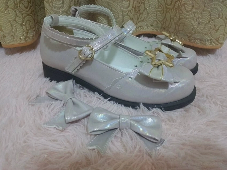 Top-down flat lay of silvery grey sweet lolita shoes with shiny patent leather upper star gold hardware ankle buckle strap displayed with matching bow accessories on fuzzy fur mat