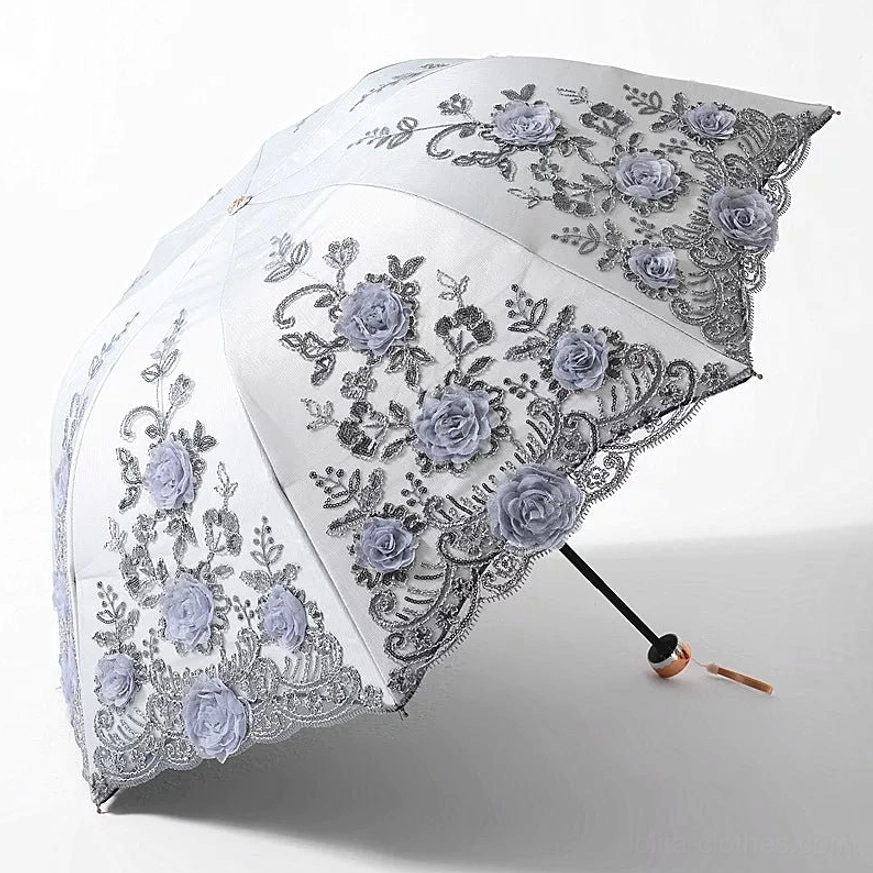 Silvery white foldable lolita floral parasol with dark purple three-dimensional roses and grey leaf embroidery, black scalloped lace edge, metal handle with hanging strap, fully opened from three-quarter top view against plain white studio background