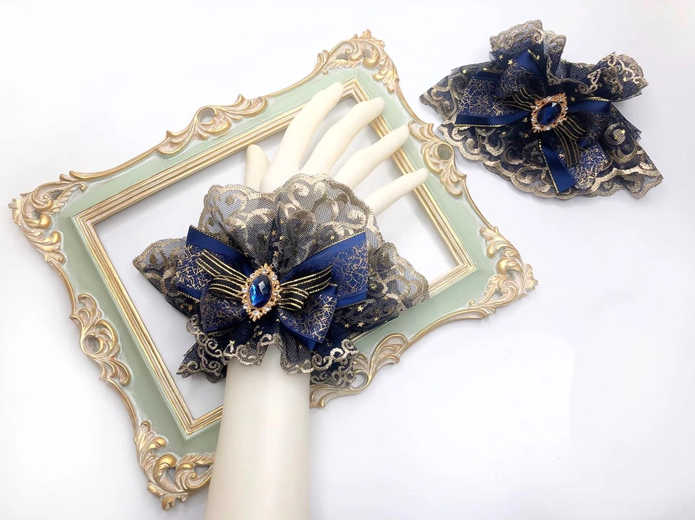 Single indigo lolita wrist cuff with matching decorative bow, featuring gothic lace base and central teardrop blue gem embellishments on white mannequin arm overhead view