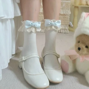 Sky blue bow Lolita lace socks close-up front view with ruffled lace cuff edge, paired with white leather Mary Jane flats in cozy indoor sweet aesthetic setting