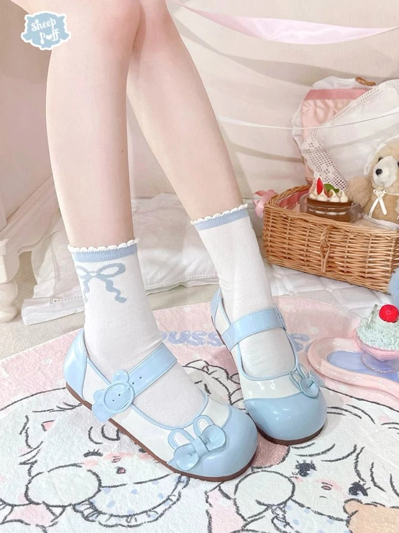 Sky blue bunny bow lolita flat shoes worn standing on cat-patterned rug with picnic basket prop showing adjustable strap and frilled coordination
