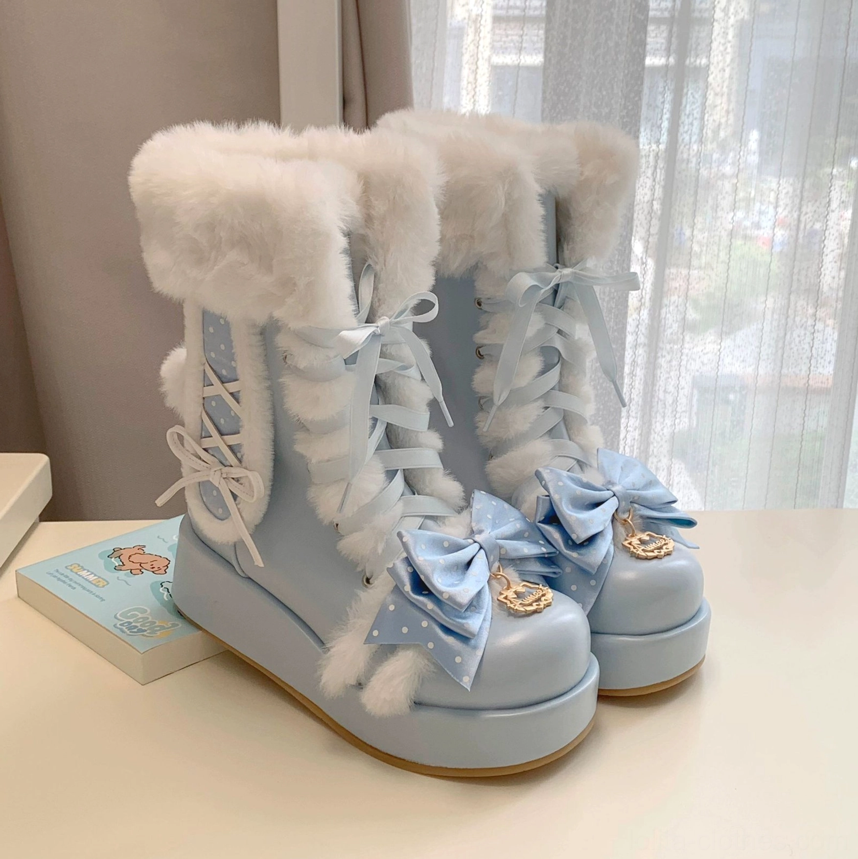 Close-up side view of sky-blue sweet lolita bunny ear platform boots on desk display, highlighting thick fluffy fur collar, side lace-up design, blue bow decoration, and rubber platform sole