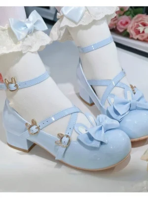 Sky blue patent leather Sweet Lolita bunny chunky heel shoes with cross ankle straps and gold bunny buckles, worn with white ruffled lace socks on vintage rose table setting, close-up side view showing glossy finish and decorative front bow