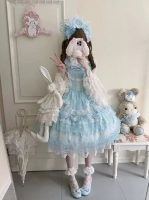 Sky blue sweet lolita JSK jumper skirt with matching detachable white lace outer sleeves and layered chiffon skirt worn by model with twin brown curls holding plush rabbit doll full body mirror selfie