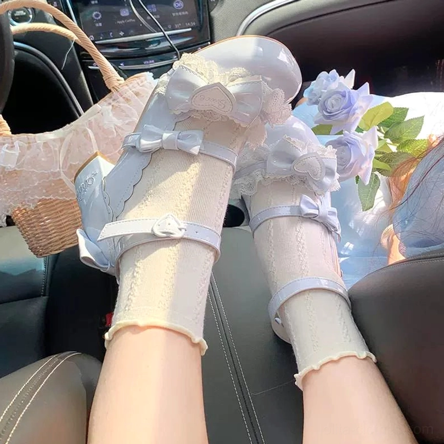 First-person close-up of sky blue sweet lolita mary jane heels being worn inside passenger car with lace bow decor ankle strap design paired with ruffled light yellow socks and blue artificial flowers