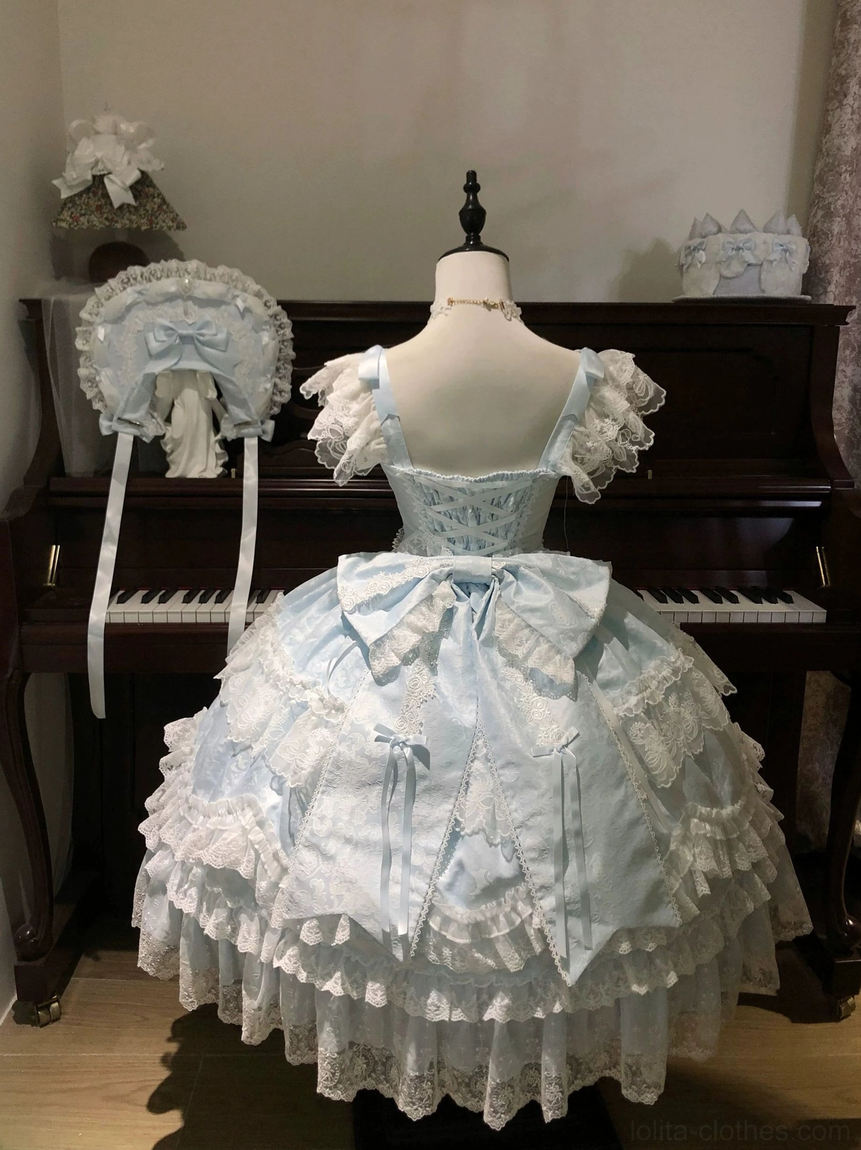 Back view of sky blue sweet lolita tiered JSK dress showing large back waist bow and layered lace skirt construction