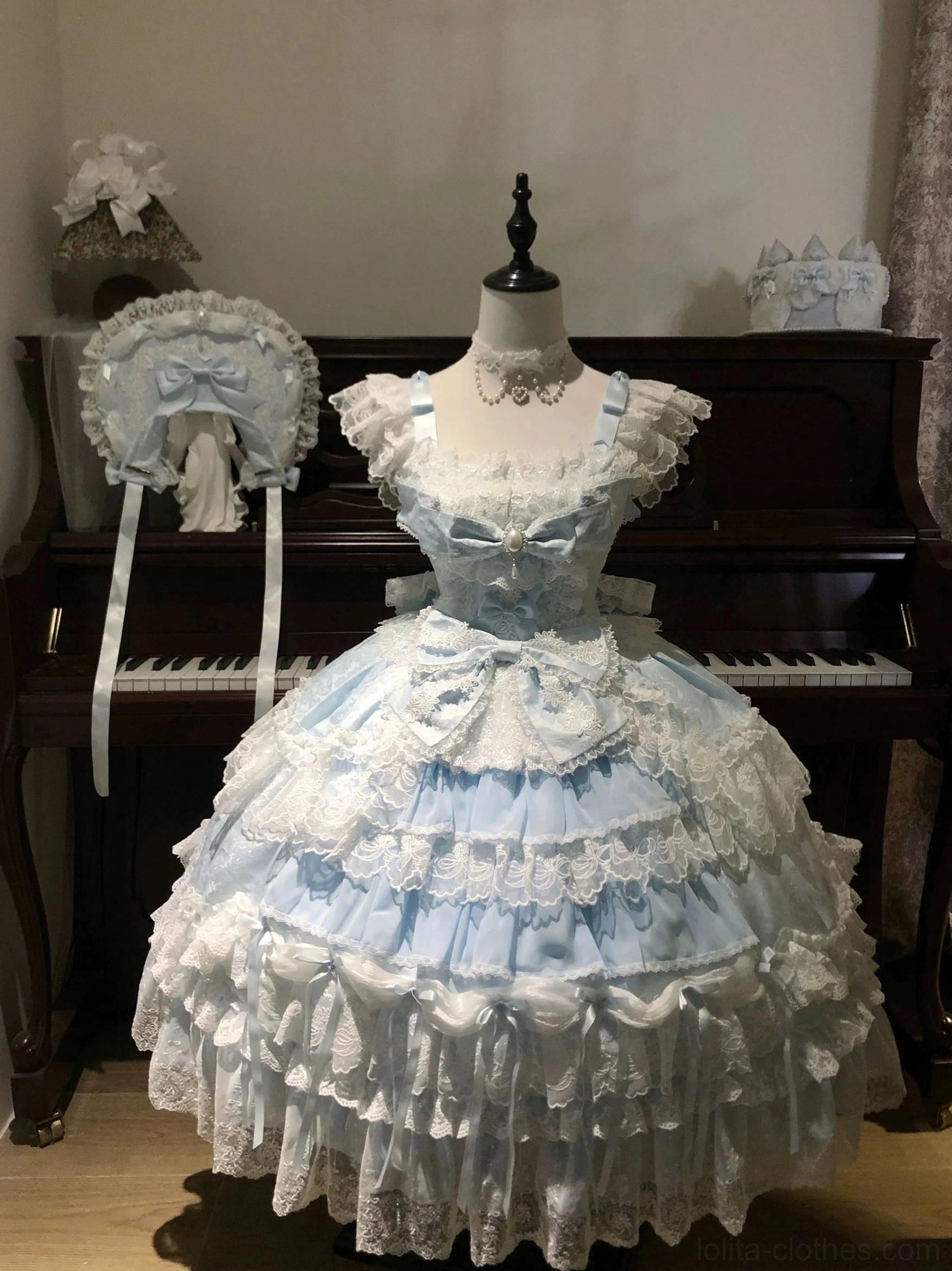 Front view of sky blue sweet lolita tiered JSK dress with white lace trims and matching bonnet on mannequin