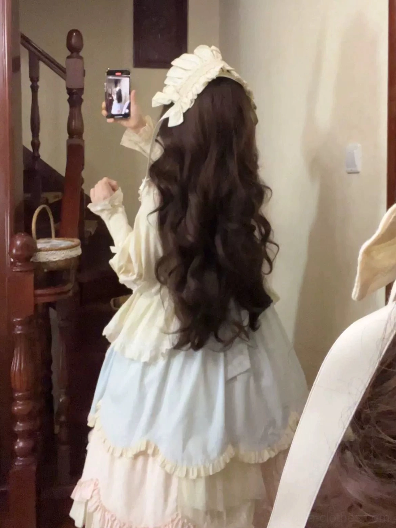 Back mirror selfie view of sweet lolita OP dress on wooden stairs showing long wavy hair with matching hairband layered ruffled back skirt elegant lolita silhouette
